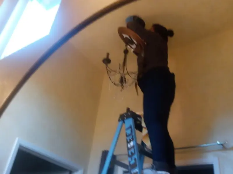 Electrician installing a chandelier in a Sunset residence
